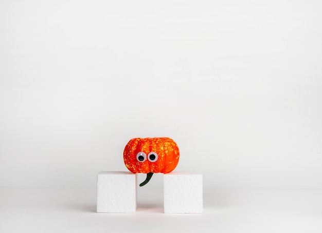 Citrouilles drôles avec des yeux sur un cube blanc Concept d'Halloween Idée créative