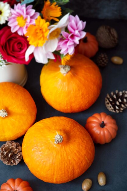 Citrouilles fraîches. Flatlay créatif d'automne, fond sombre avec des bougies, des fleurs d'automne, des pommes de pin et des citrouilles. Vue de dessus.