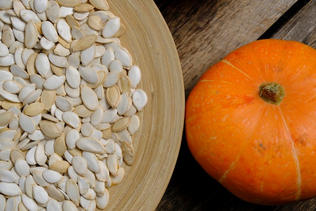 Photo citrouilles et graines de citrouille dans une assiette sur fond de bois