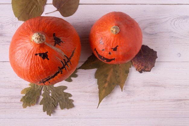 Les citrouilles d'Halloween se tiennent sur les feuilles d'automne