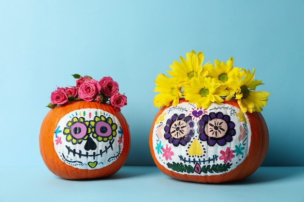 Citrouilles avec maquillage de crâne de catrina et fleurs sur bleu