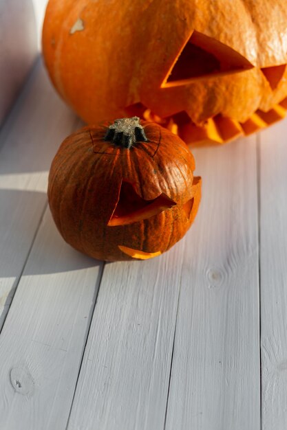 Citrouilles orange effrayantes sur une table en bois blanche Joyeux halloween