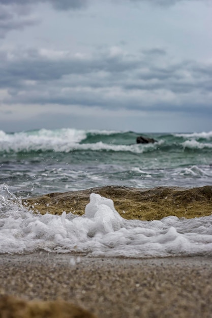 Éclaboussure d'écume de mer sur le rivage de la mer Noire Bouchent les vagues d'eau de mer avec des bulles sur la plage de sable