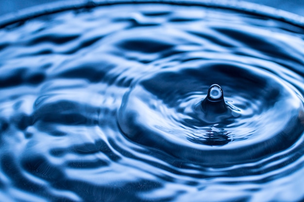 Éclaboussure de goutte d'eau dans un verre de couleur bleue