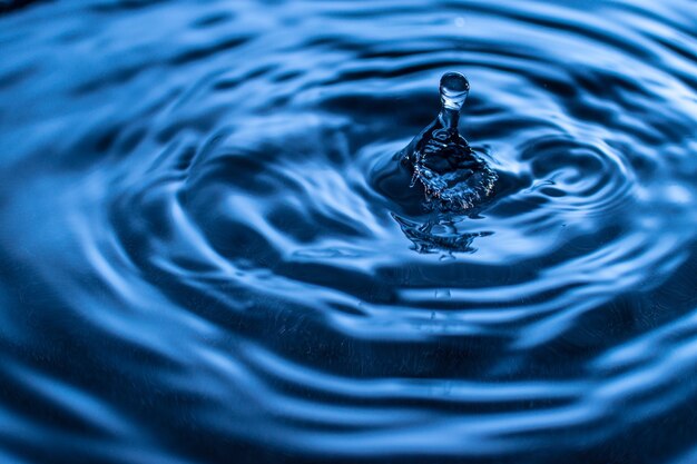 Éclaboussure de goutte d'eau dans un verre de couleur bleue