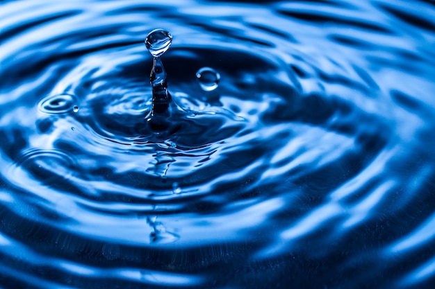 Éclaboussure de goutte d'eau dans un verre de couleur bleue