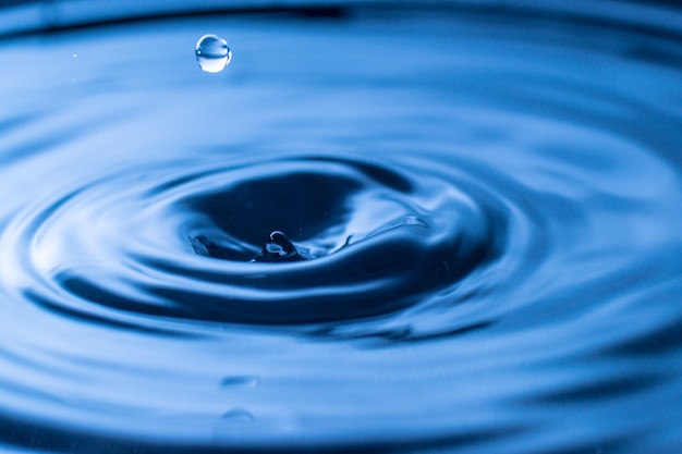 Éclaboussure de goutte d'eau dans un verre de couleur bleue