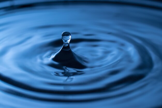 Éclaboussure de goutte d'eau dans un verre de couleur bleue