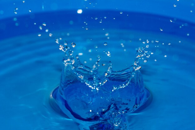 Éclaboussure de goutte d'eau dans un verre de couleur bleue