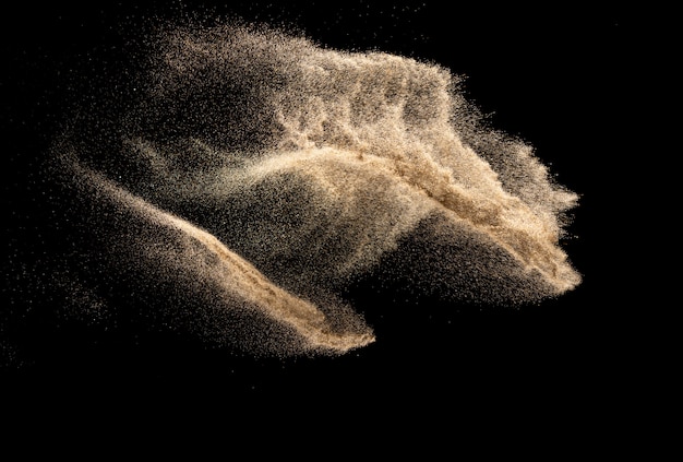 Éclaboussure de sable de couleur brune.Explosion de sable de la rivière sèche isolée sur fond noir. Nuage de sable abstrait.