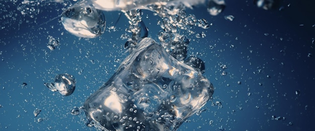 Éclaboussures d'eau et glaçons Glace éclaboussant dans un verre d'eau Sous l'eau versant des glaçons tombant dans un fond d'arrosage clair Refroidissement rafraîchissant buvant des glaces dans un verre avec fond bleu