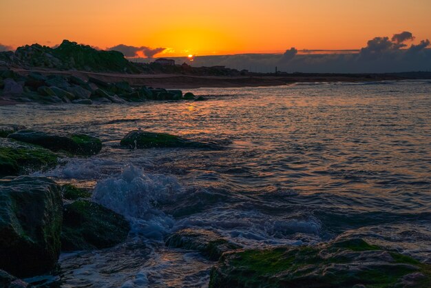 Éclaboussures de vagues sur les falaises côtières au coucher du soleil