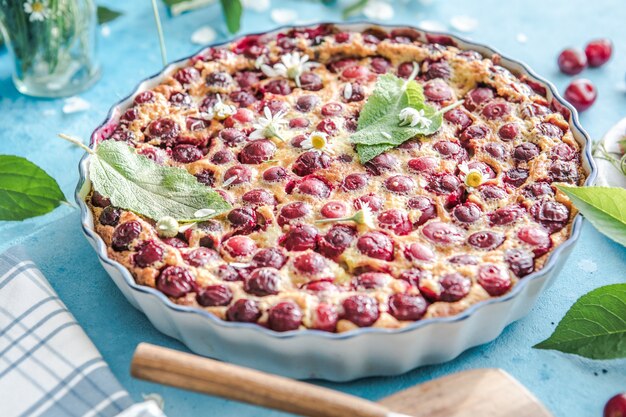 Clafoutis aux cerises avec cerise sur fond bleu