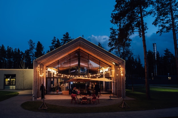 Éclairage du soir dans la cour avec le fond d'une maison en bois moderne