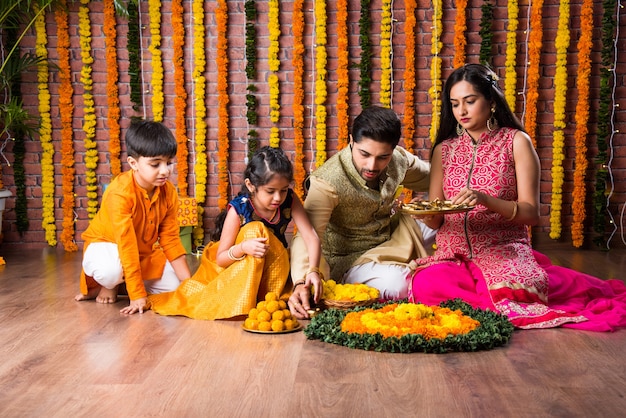 Éclairage familial indien ou organisation d'une lampe à huile ou diya autour d'un rangoli de fleurs le soir du festival de diwali