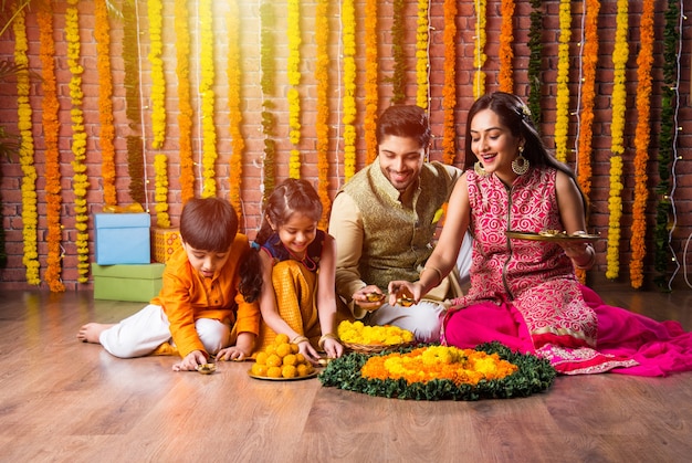 Éclairage familial indien ou organisation d'une lampe à huile ou diya autour d'un rangoli de fleurs le soir du festival de diwali