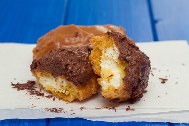 Éclairs au chocolat sur papier blanc sur une surface en bois