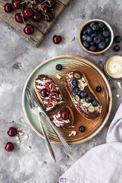 Éclairs avec garniture au chocolat noix et baies sur fond de béton