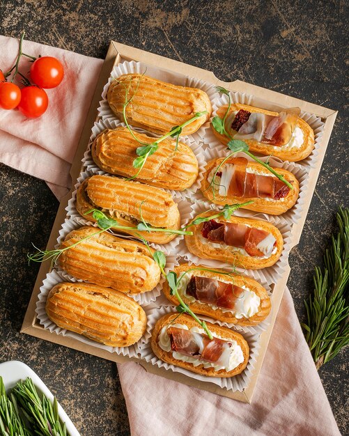 Éclairs gourmands remplis de fromage à la crème et de prosciutto sur un plateau garni de papier