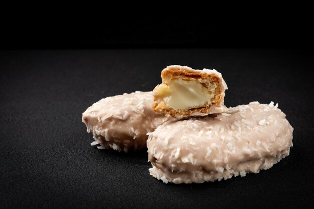 Éclairs de noix de coco ou biscuits à la crème sur fond noir.