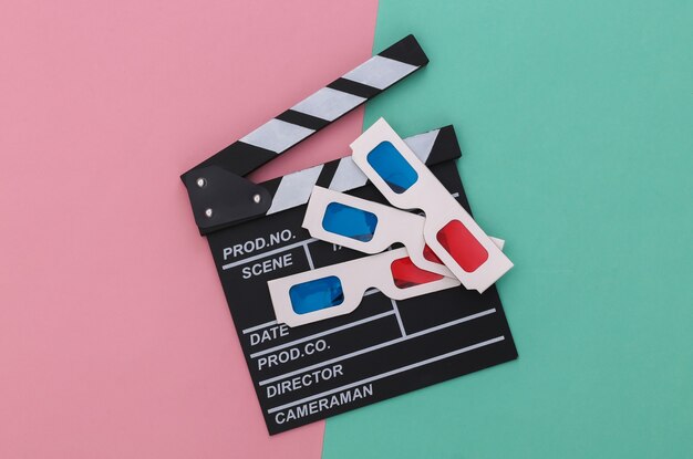 Clap de cinéma avec lunettes 3d rétro sur fond pastel bleu rose. Cinéma, réalisation de films, production de films, industrie du divertissement. Vue de dessus