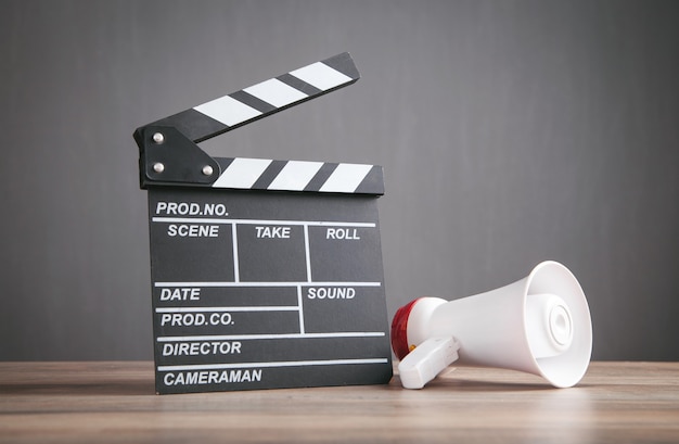 Clap de cinéma et mégaphone sur la table en bois.