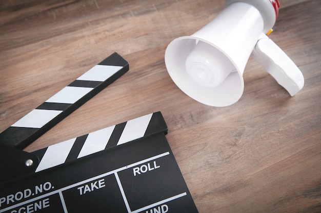 Clap de cinéma et mégaphone sur la table en bois.