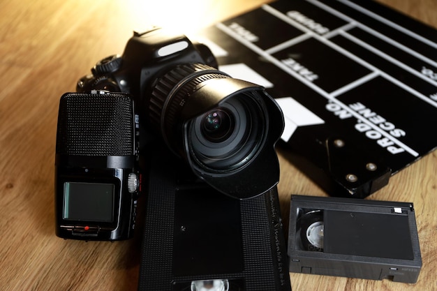 Clap de film avec une caméra, un micro et une cassette VHS sur bois.
