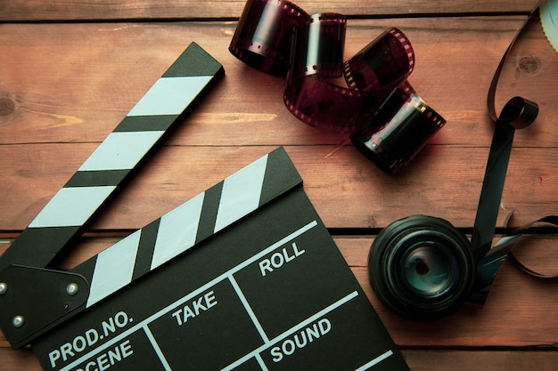 Clap de film, pellicule et lentilles sur table en bois