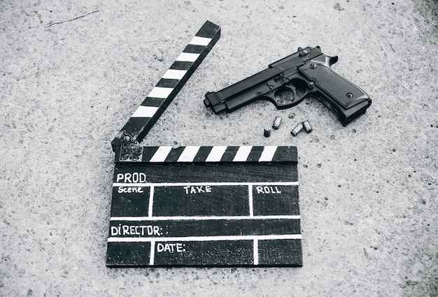 Clap noir avec pistolet sur fond. Réalisation et tournage de film de cinéma. Histoire criminelle de détective.