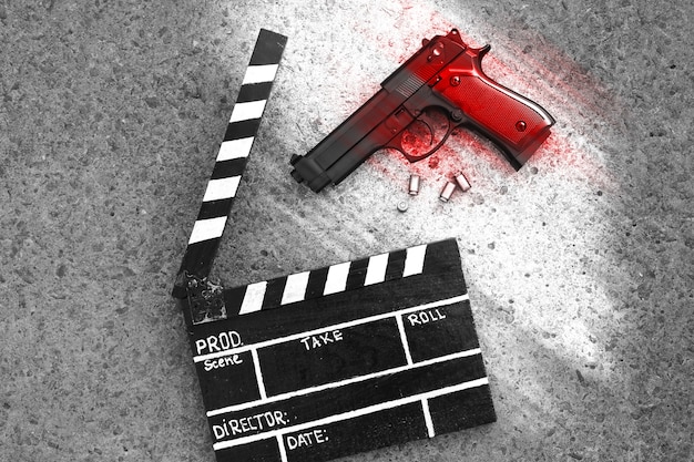 Photo clap noir avec pistolet sur fond. taches rouges comme du sang. réalisation et tournage de film de cinéma. histoire criminelle de détective.