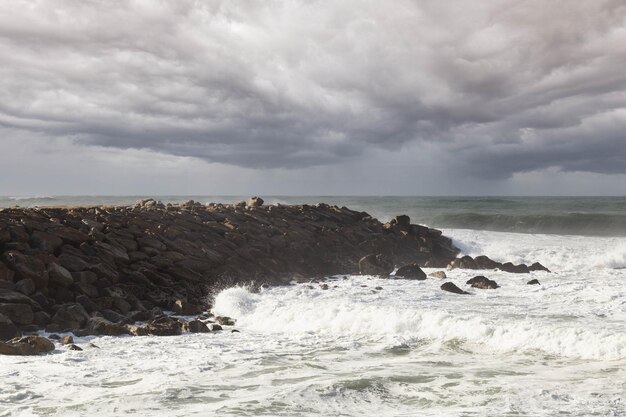Clapotis de la mer contre les rochers, avec un ciel nuageux sur la plage de Furadouro au Portugal
