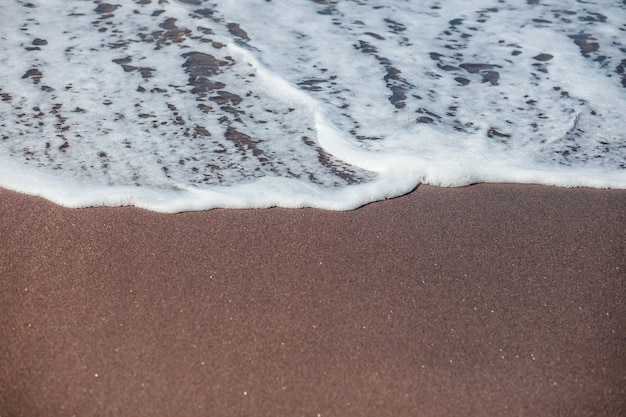 Le clapotis des vagues sur le sable noir