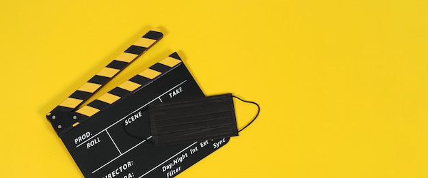 Clapper board ou ardoise de film et masque facial noir sur fond noir jaune. Couleur jaune et noire.