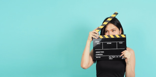 Photo clapper board ou clap de cinéma dans la main de la femme avec une couleur noire et jaune sur fond menthe