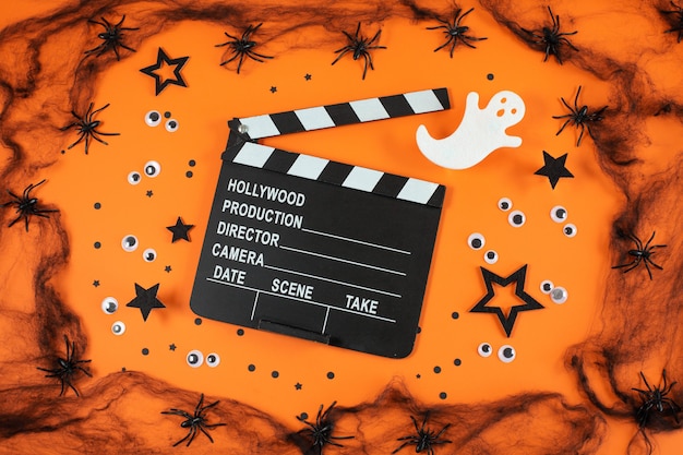 Clapper board dans les toiles d'araignées araignées fantômes yeux sur fond orange