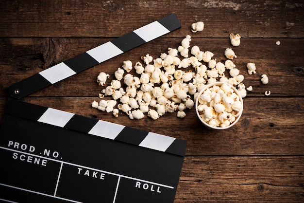 Clapper board et pop-corn sur fond de bois, vue de dessus en gros plan