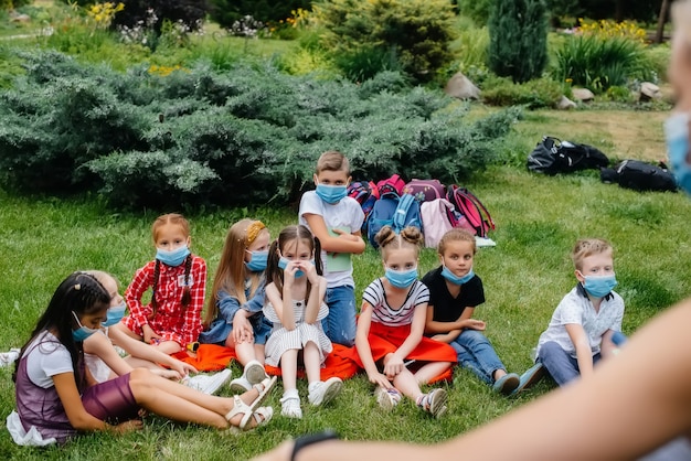 Une classe d'écoliers masqués est engagée dans une formation en plein air pendant l'épidémie