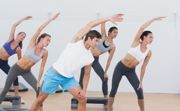 Classe faisant des exercices d&#39;étirement en studio de fitness