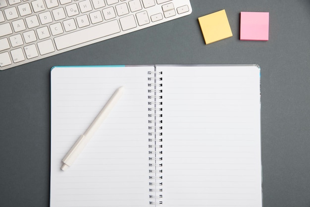 Clavier au-dessus d'une table à côté d'un ordinateur portable et de stylos avec un clavier d'ordinateur de notes collantes au-dessus d'un