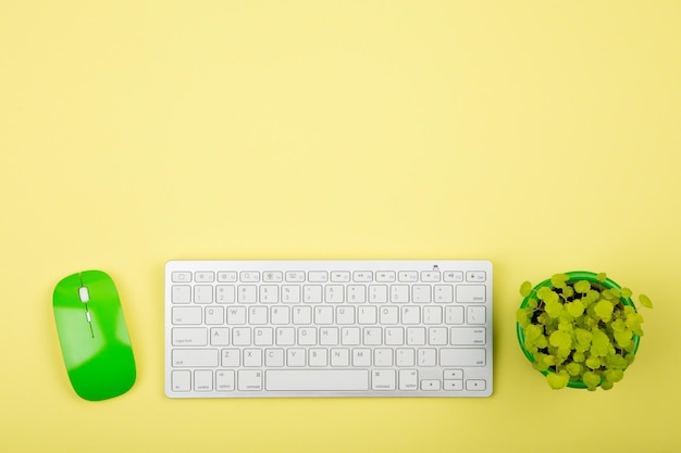 Clavier blanc mince sans fil et souris verte sur fond jaune