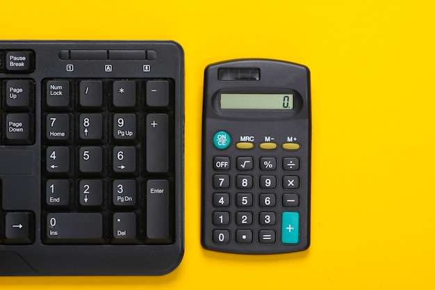 Photo clavier et calculatrice pc sur jaune. espace de travail