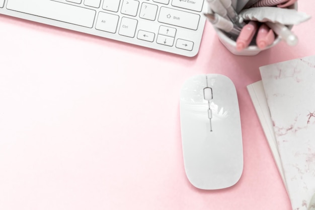 Un clavier d'espace de travail féminin d'un ordinateur sur fond rose avec un espace de copie