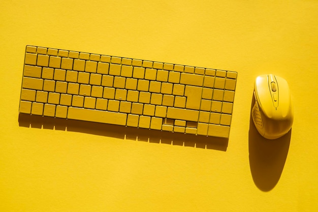 Clavier jaune et souris d'ordinateur jaune sur fond jaune Vue de dessus mise à plat