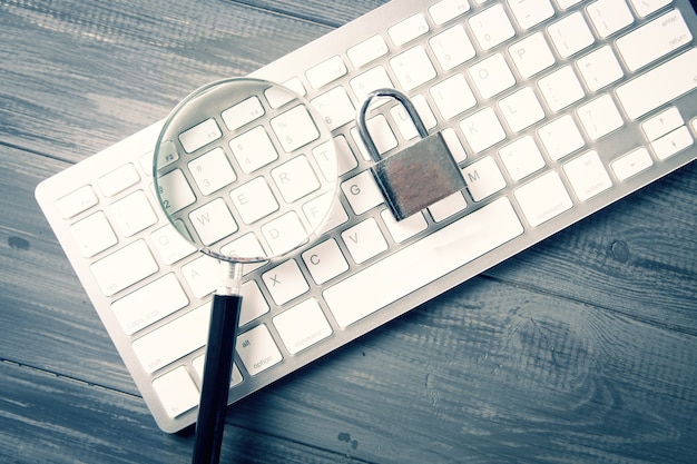 Clavier, loupe et serrure. concept de recherche de protection. défenses apprises. table en bois grise