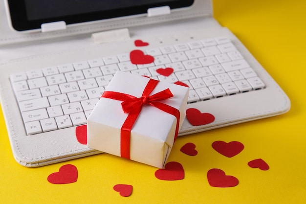 Clavier d'ordinateur blanc et coeur de cadeau sur fond jaune Achats en ligne de cadeaux de la Saint-Valentin