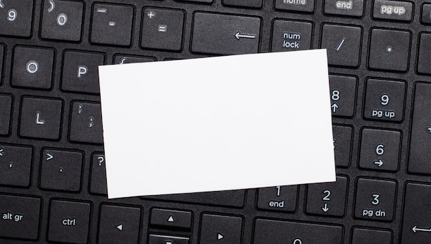 Le clavier de l'ordinateur a une carte vierge blanche pour insérer du texte. Modèle. Vue de dessus avec espace copie