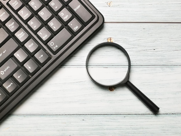 Clavier d'ordinateur avec loupe sur la table en bois Concept de recherche Internet