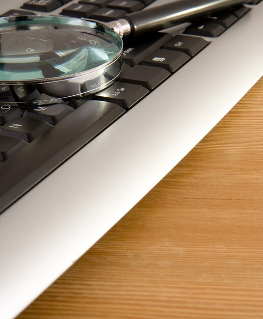 Clavier d'ordinateur et loupe sur table en bois