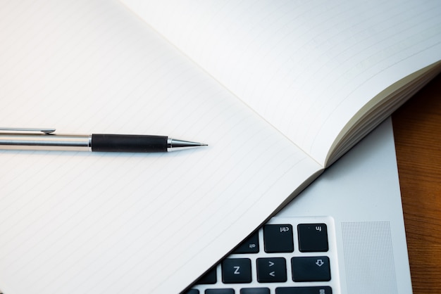 Clavier d'un ordinateur portable d'en haut avec un bloc-notes et un stylo.